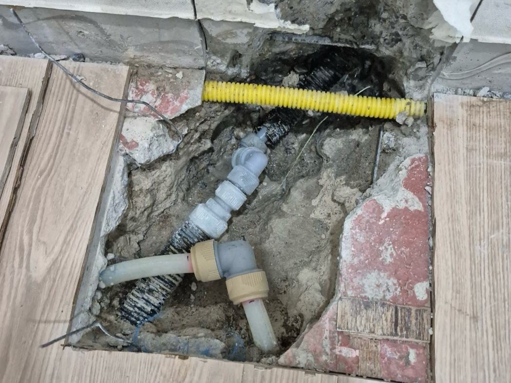 1층 바닥을 뚫은 자리에서 새 배관을 잇는 중