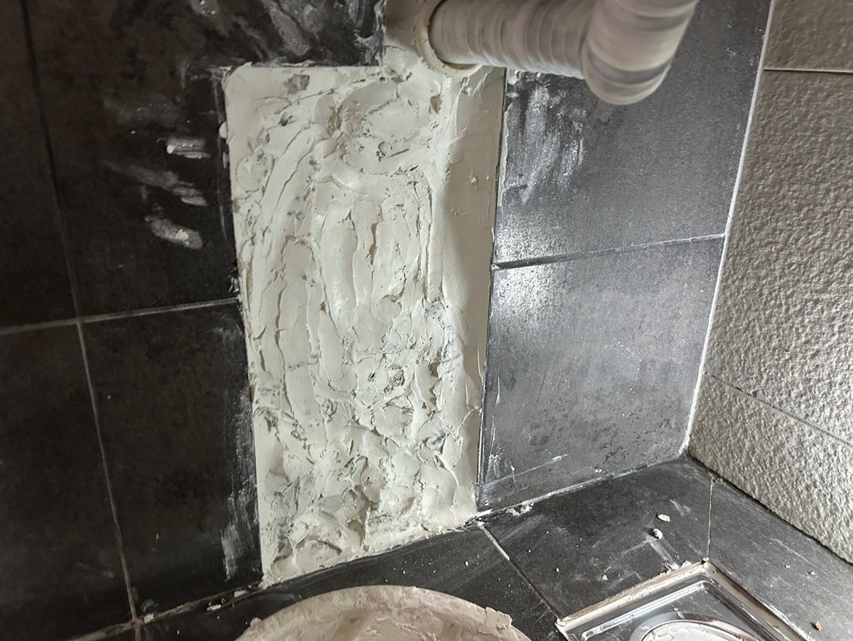벽 속 세면대 하수관을 열어 확인한 뒤 다시 메운 자리