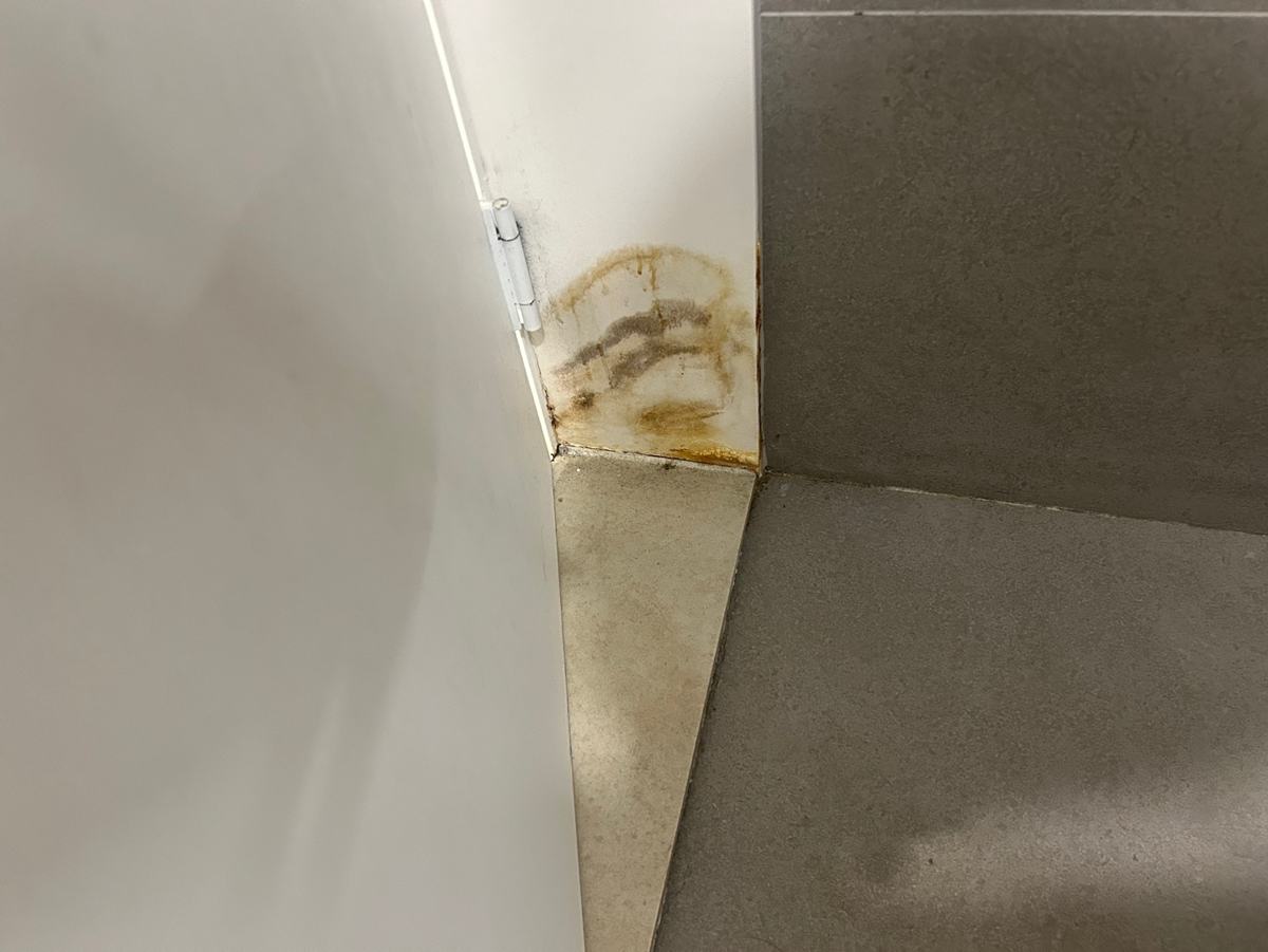 화장실 앞 문틀 아래로 번진 물 자국